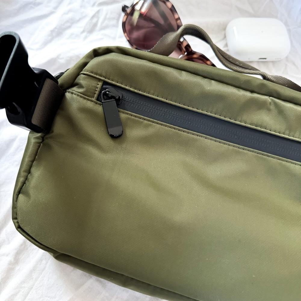 Close up image of hidden back pouch perfect for storing your phone. Waterproof material and waterproof zipper. Green dog walking bag featuring a detachable treat pouch, perfect for training and walks. Practical dog walking bag for storing treats, waste bags, and dog accessories.