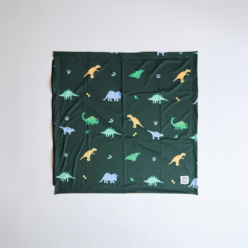 Jurassic Bark dinosaur-themed cooling mat for dogs by Taylor and Floof. Dog cooling mat with fun dino print, perfect for summer outings. Non-gel, ice silk fabric dog cooling mat.