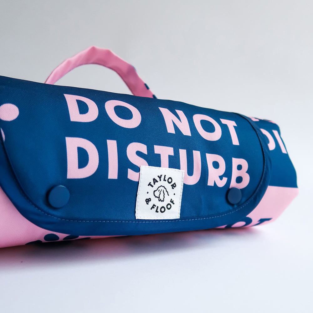 Rolled view of Do Not Disturb dog settle mat showing popper closure, compact and portable for walks, cafés and public transport.