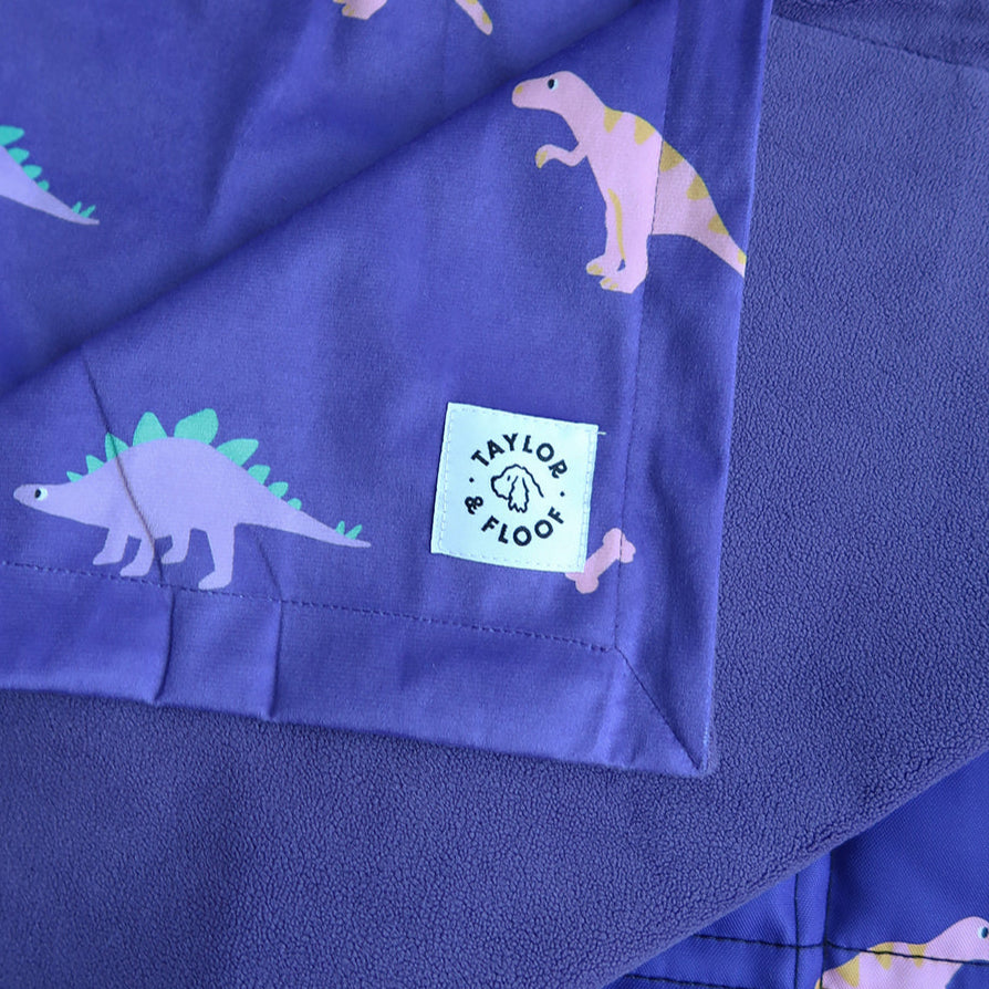 Purple fleece fabric with dinosaur patterns and a visible brand label.