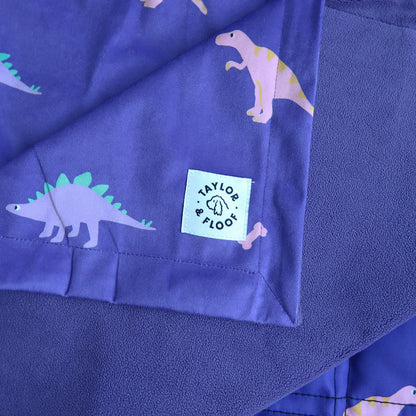 Purple fleece fabric with dinosaur patterns and a visible brand label.
