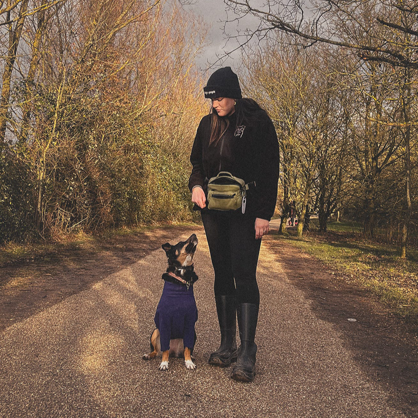 Discover the perfect dog walking bag! UK-based, waterproof designs, Lightweight, durable & ready for every walk. Woman with her dog in the forest using our green dog walking bag.