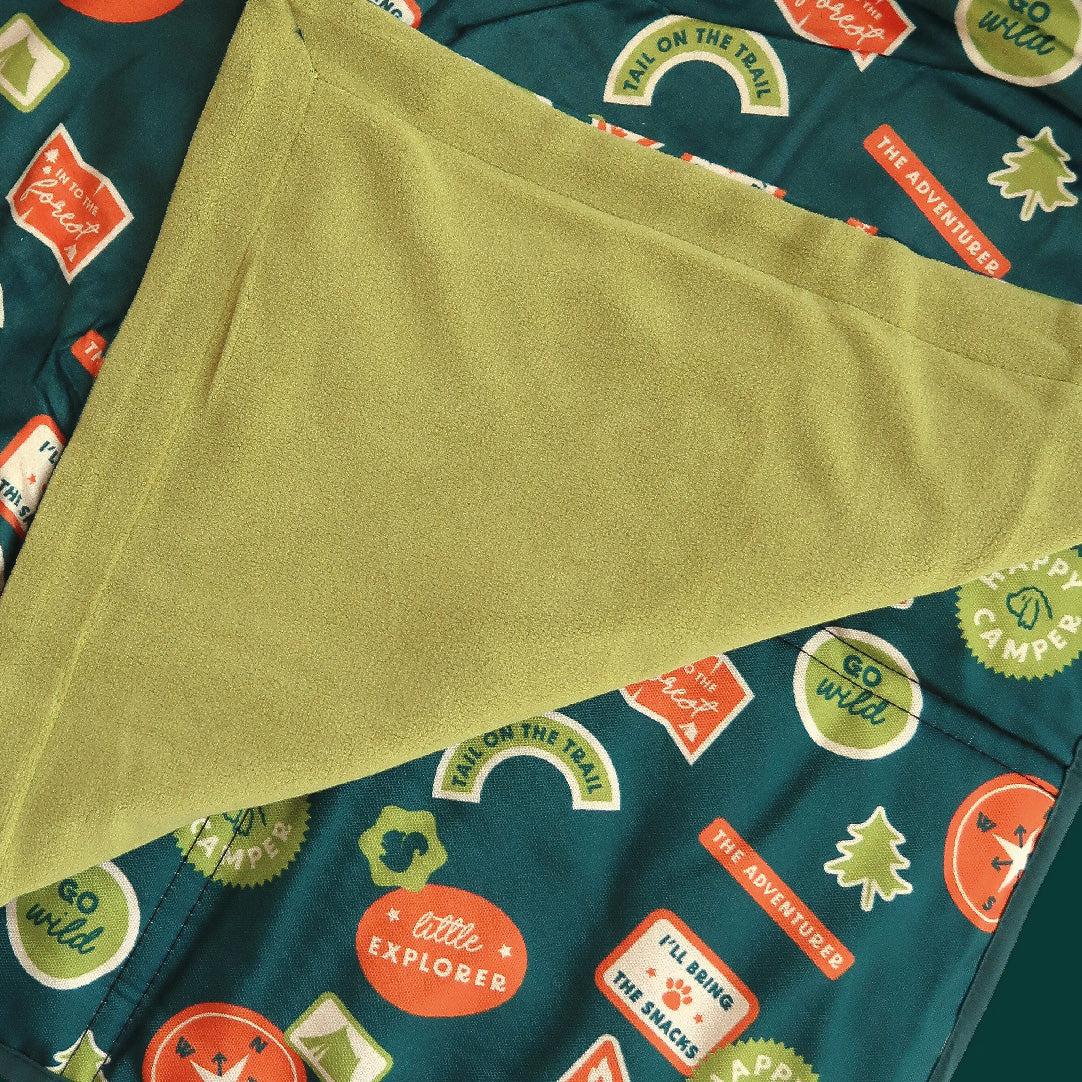 Green fabric with a pattern of colorful text and shapes on a teal background