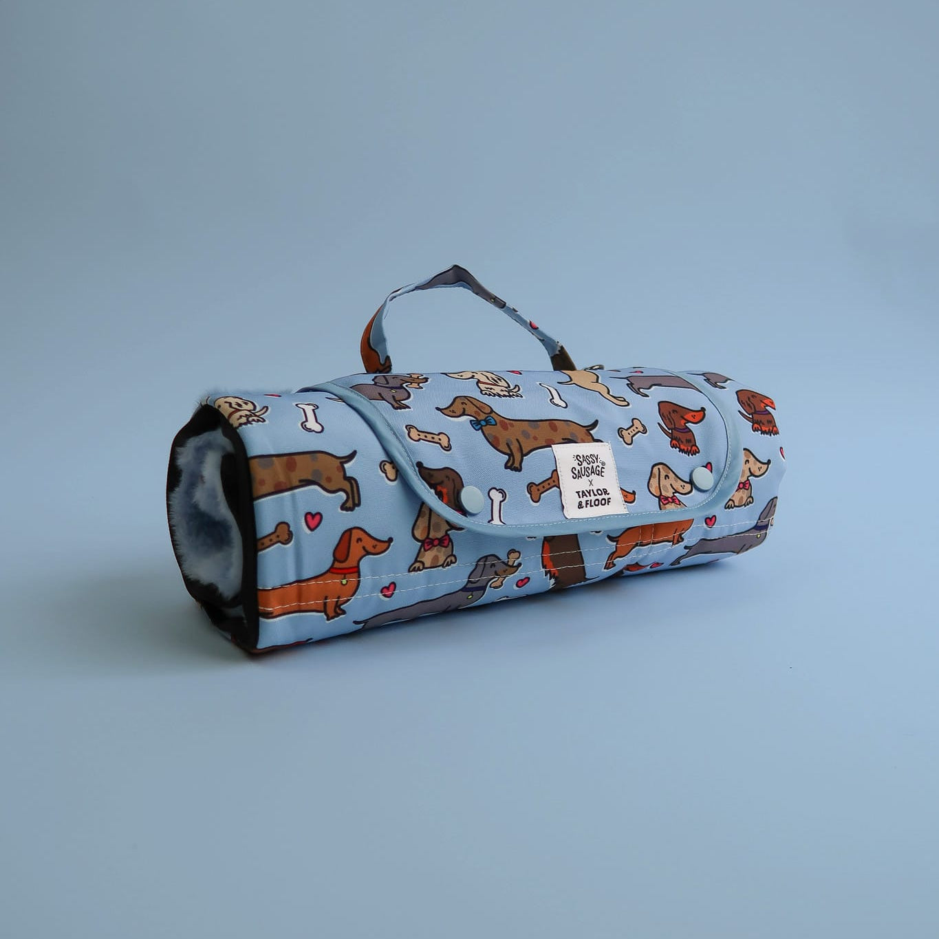 Waterproof dog settle mat in a lovely dachshund resign. Rolled up for potable use on a blue background.