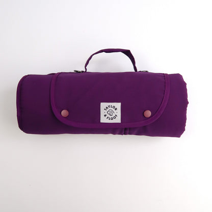 Rolled up small plum settle mat on a white ba grround 