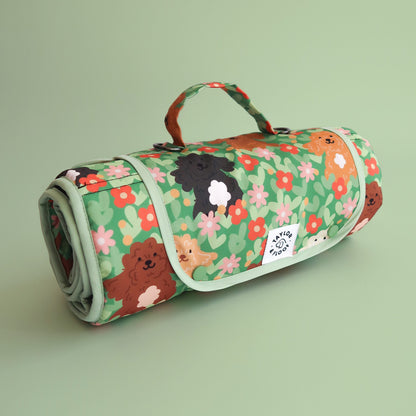 Rolled up settle mat with cockapoo and doodle dog illustrations with flowers on a light green background. Portable dog mat for training, travel, and creating calm spaces for dogs anywhere.