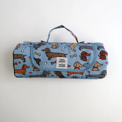 Foldable dog mat with dachshund pattern on a blue background. Sassy Sausage and Taylor and Floof collaboration 