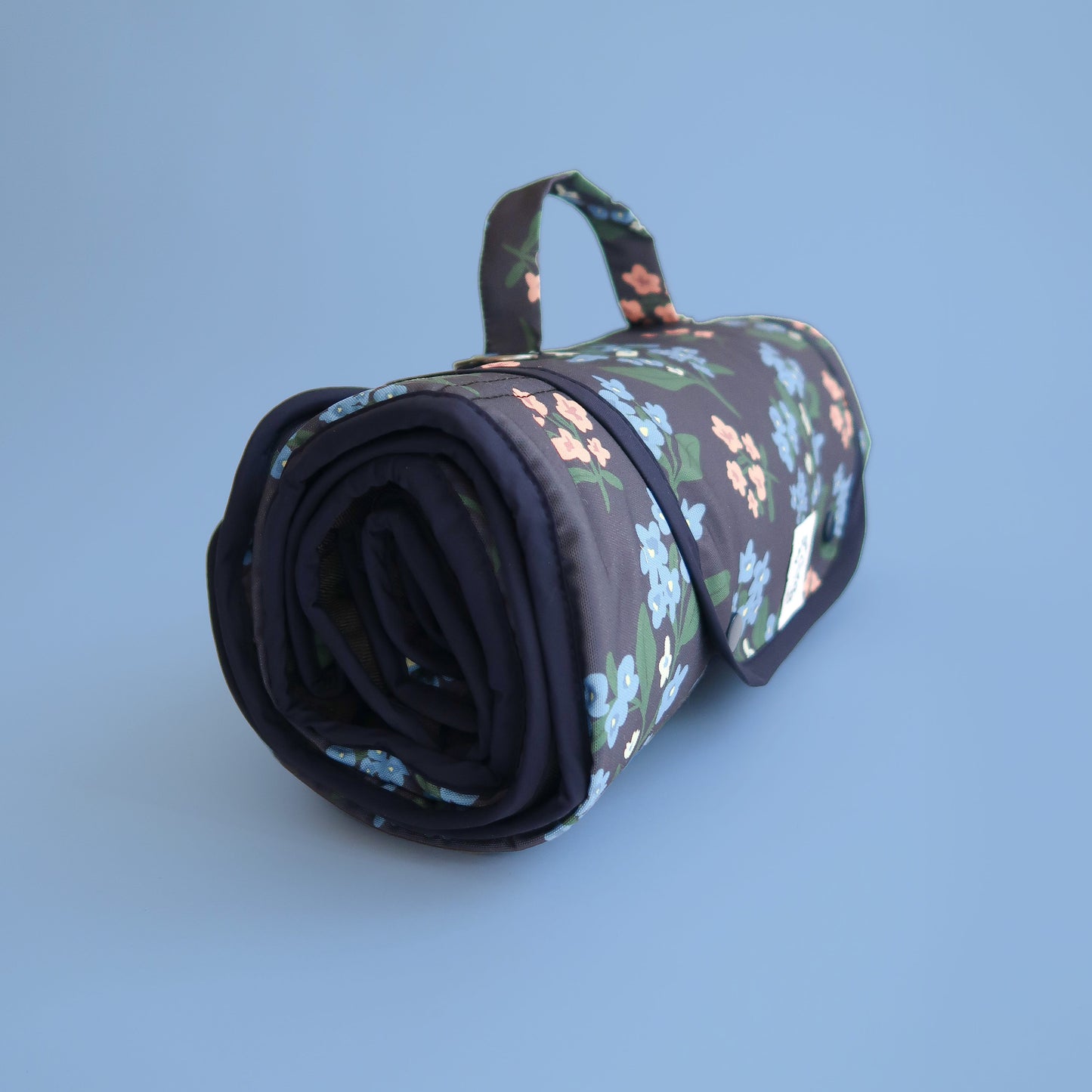 Roll-up floral-patterned settle mat with handle on a light blue background