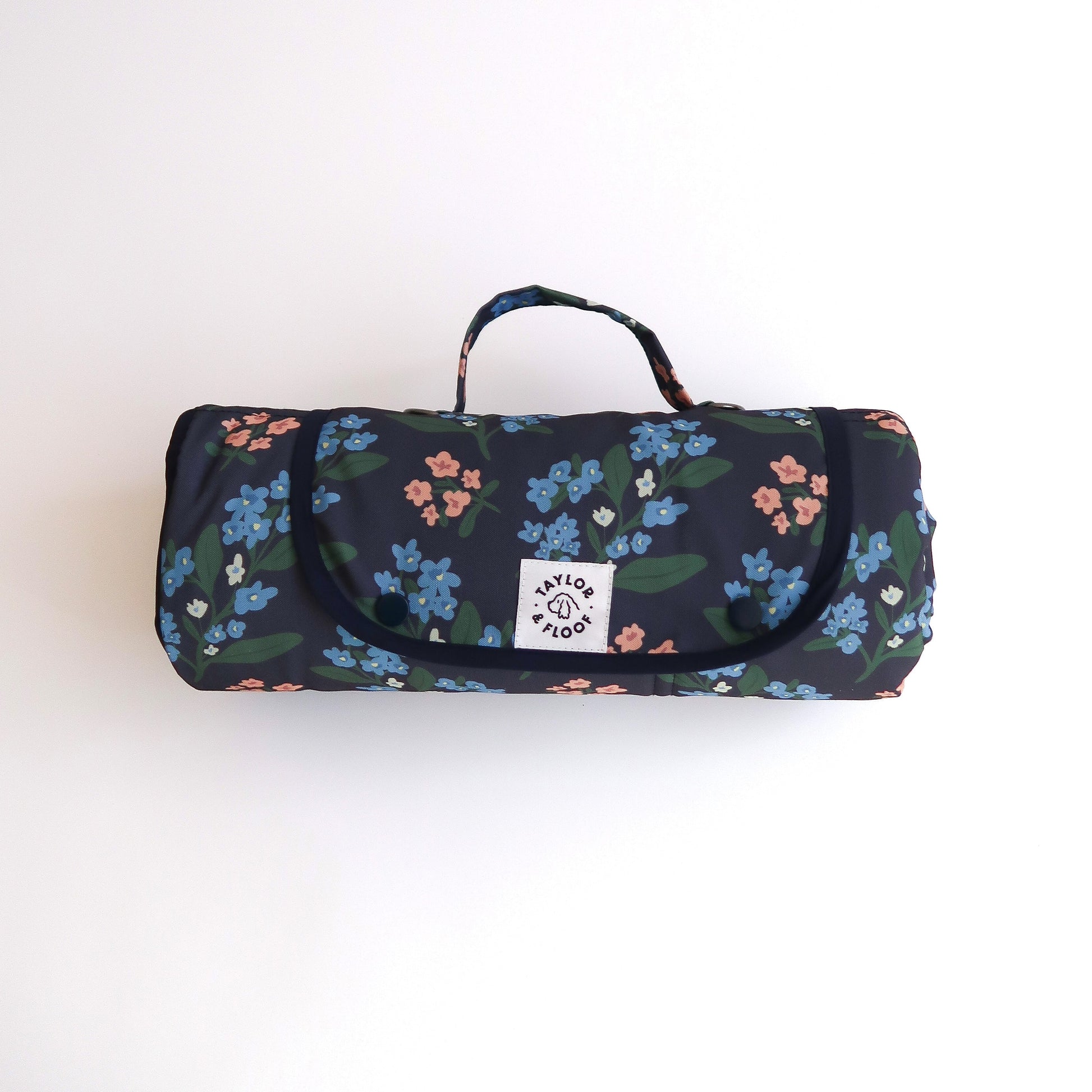 Dark blue settle mat for dogs with pink and blue florals on. On a white background with a taylor and floof logo