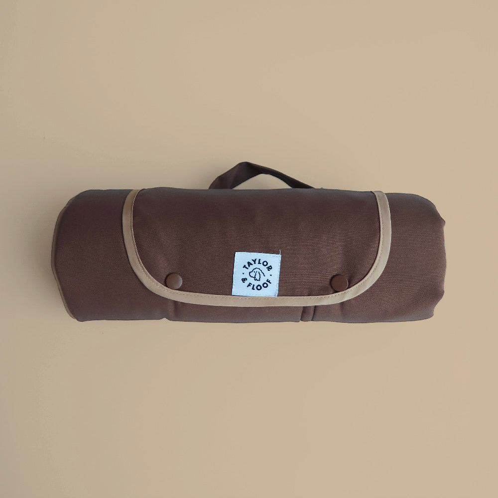 Brown roll-up mat with a visible brand logo on a beige background. Foldable mocha brown dog training mat with carry straps, compact and portable design.