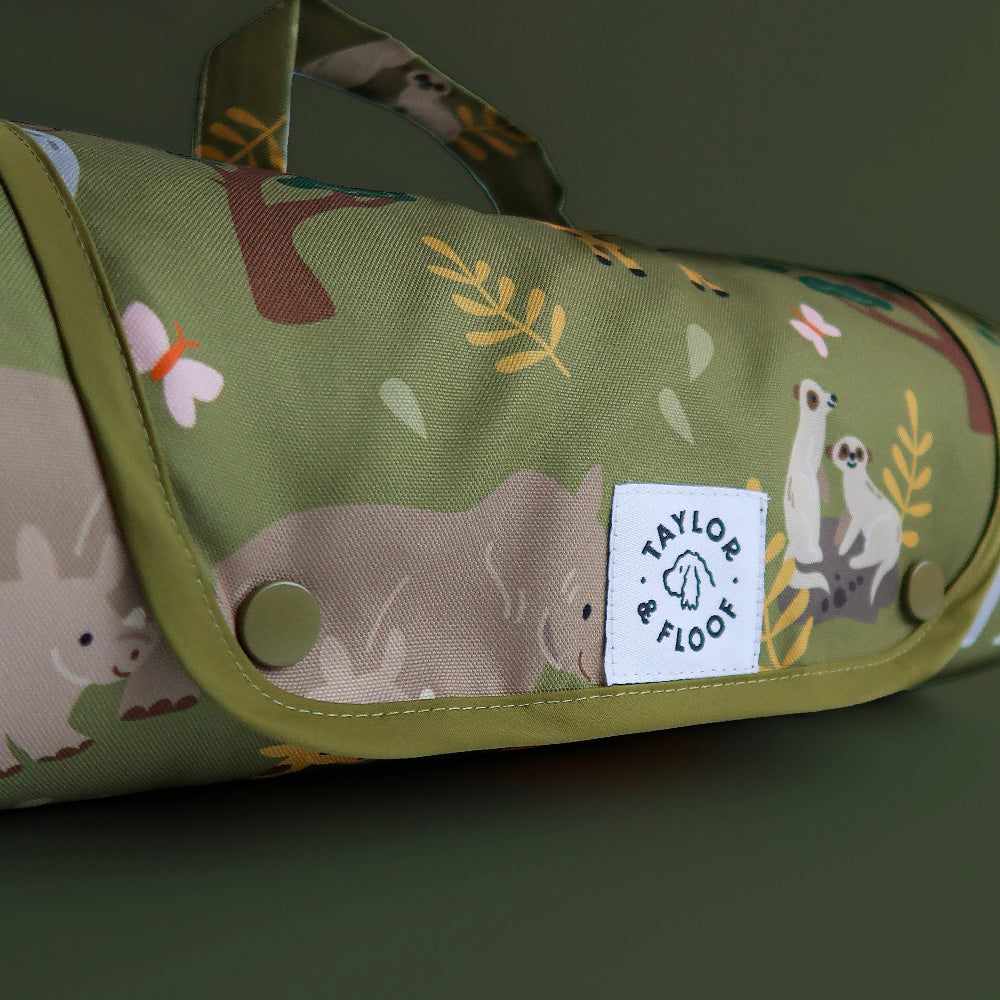 Green settle mat rolled up with Safari animal patterns and a visible brand label on a dark green background
