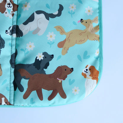 Dog settle mat with cartoon spaniel pattern on a light blue background. Brown and black cocker spaniels walking together, with a cream show cocker spaniel running around with its tongue out. Pattern also includes a king charles spaniels and black and white springer spaniels. 
