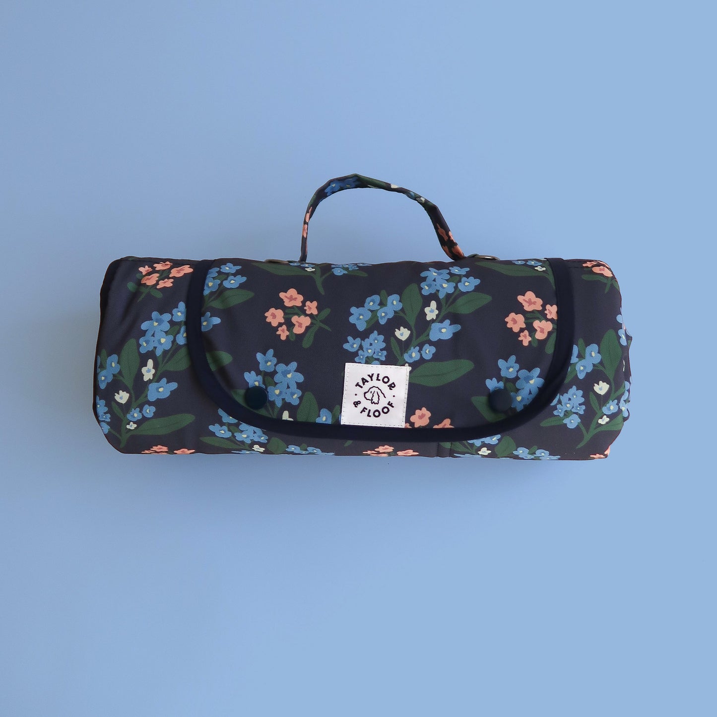 Floral-patterned settle mat or travel mat for dogs with a handle on a blue background