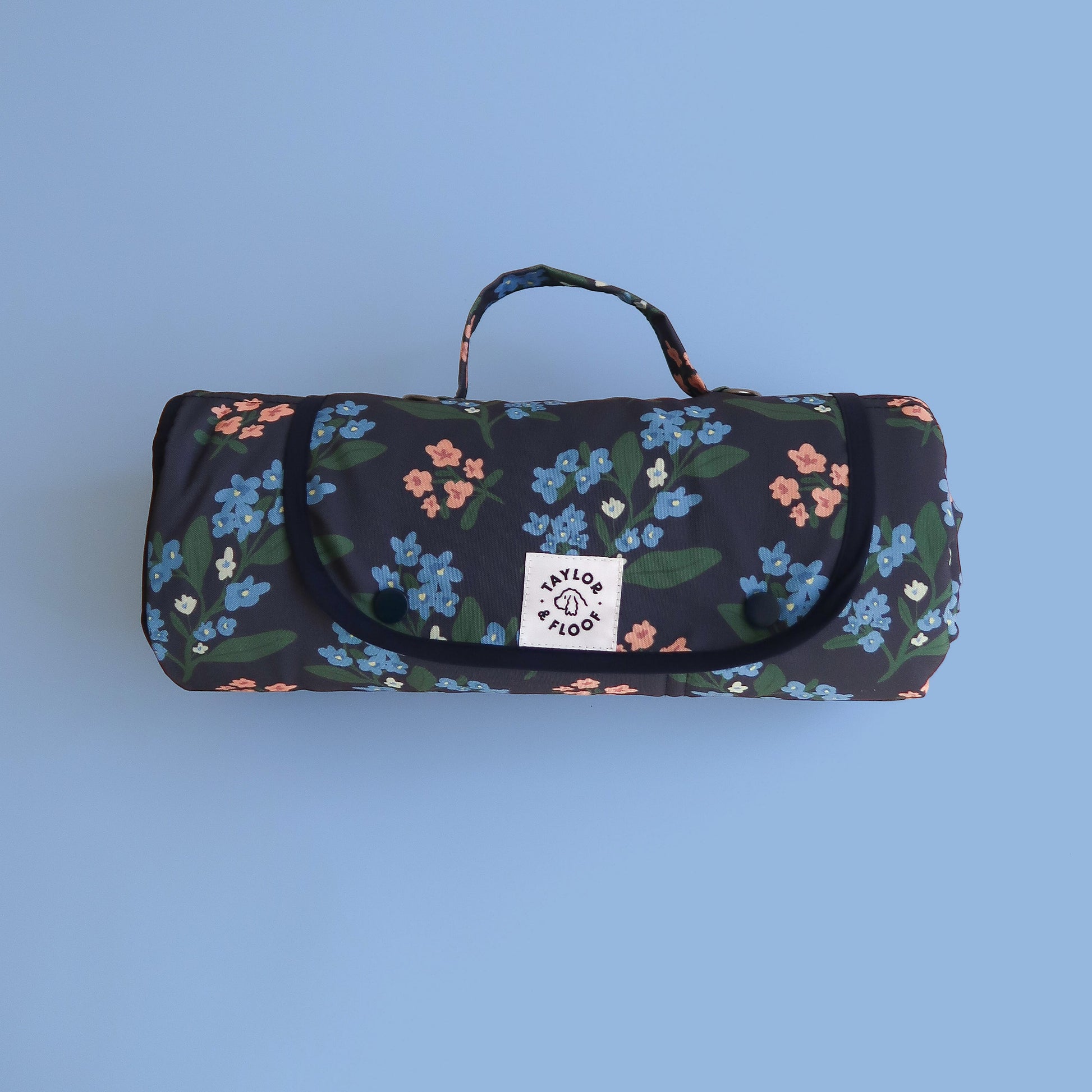 Floral-patterned settle mat or travel mat for dogs with a handle on a blue background